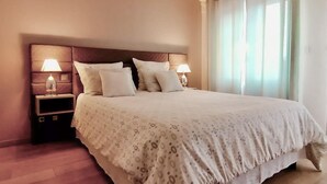 A neatly made bed with a patterned bedspread, two bedside lamps, and a nightstand with a lamp. - Lovely home in Lorgues (Lorgues)