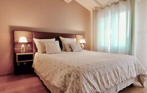 A neatly made bed with a patterned bedspread, two bedside lamps, and a nightstand with a lamp. - Lovely home in Lorgues (Lorgues)
