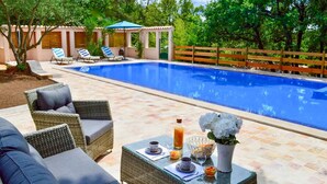 A swimming pool with lounge chairs, a covered seating area, and a table with drinks and snacks. - Lovely home in Lorgues (Lorgues)