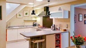A modern kitchen with a central island, pendant lighting, and a built-in microwave. - Lovely home in Lorgues (Lorgues)