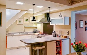 A modern kitchen with a central island, pendant lighting, and a built-in microwave. - Lovely home in Lorgues (Lorgues)