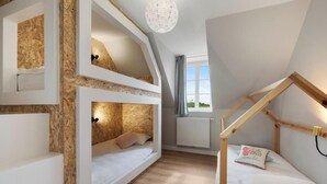 Ein Schlafzimmer im Loft-Stil mit schrägem Dach, eingebauten Holzböden und einem Schlafplatz in Form eines Hochbettes sowie einem kleinen hölzernen Bett.