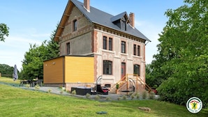 Ein großes Backsteinhaus mit einem gelben Anbau, einer Schaukel und einem kleinen Garten.