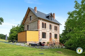 Ein großes Backsteinhaus mit einem gelben Anbau, einer Schaukel und einem kleinen Garten.