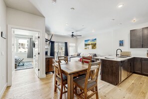 A modern kitchen with wooden cabinetry, a dining area with a wooden table and chairs, and a ceiling fan. - Mountain view condo w/ shared pool, hot tub, gym (Keystone)
