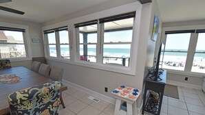A room with a dining table, chairs, a small table with toys, and large windows overlooking the beach. - Krazy Krab - Oceanfront in Garden City Beach (Garden City)