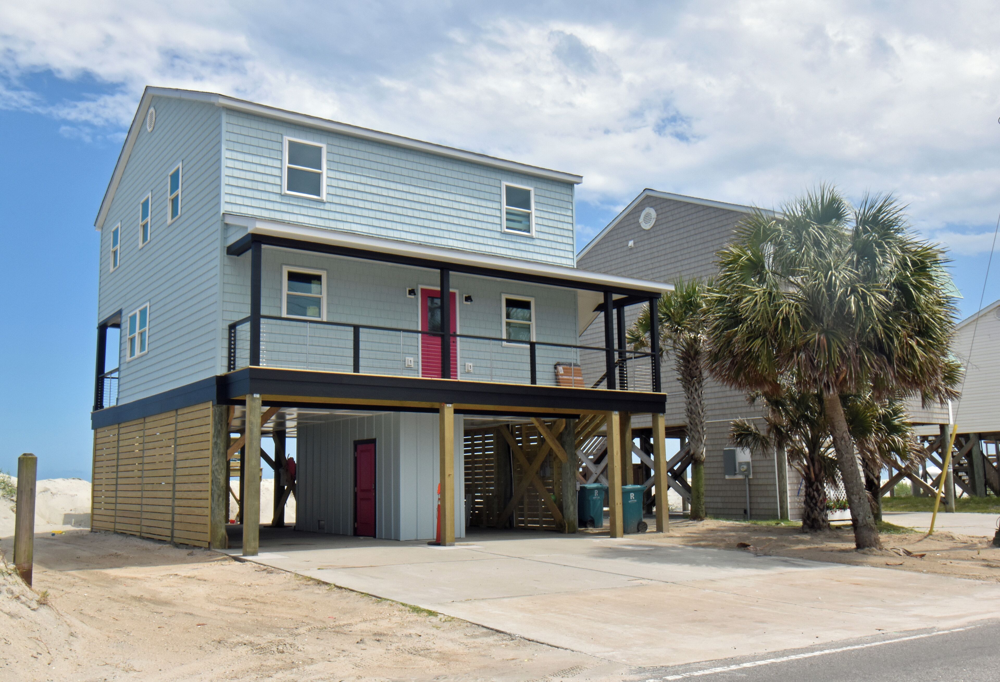 A two-story building with a covered front porch, a red door, and a balcony.