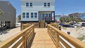 A wooden deck leading to a two-story building with a balcony and a staircase. - Krazy Krab - Oceanfront in Garden City Beach (Garden City)