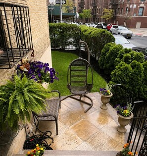 A balcony with a chair, potted plants, and a view of the street.