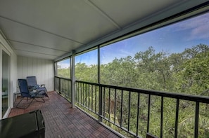 Ein überdachter Balkon mit Blick auf dichtes Grün.