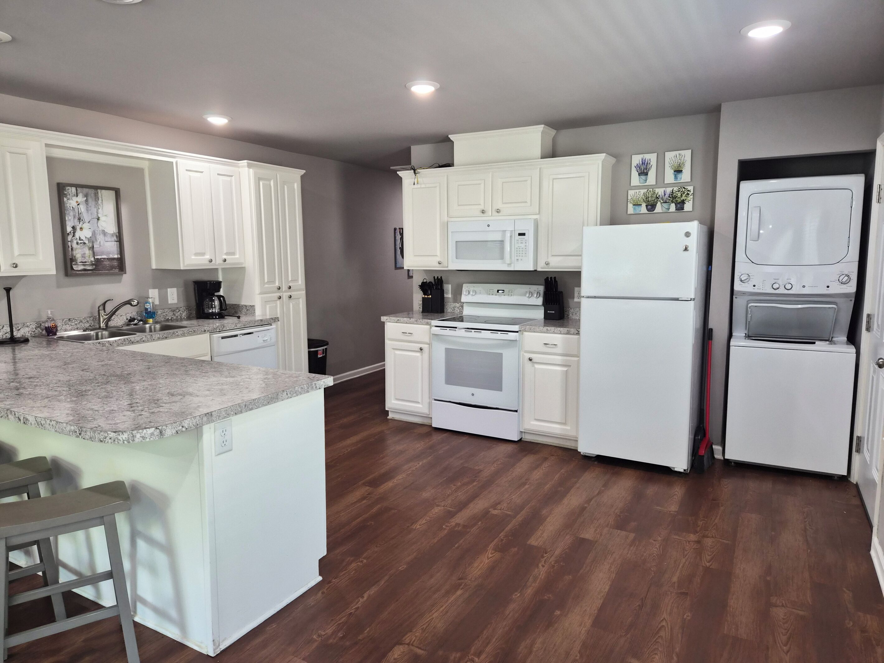 A modern kitchen with white cabinetry, a granite countertop, a built-in oven, a microwave, and a refrigerator.