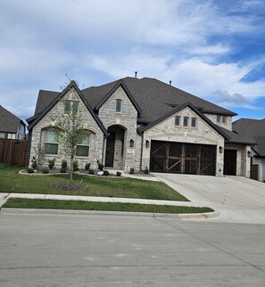 A two-story stone house with a garage, a driveway, and a well-maintained lawn. - Songbird Luxury Retreat — a Modern 4BR Getaway in Wylie, Near Lake Lavon (Wylie)