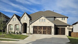 Une maison à deux étages avec une façade en pierre, un garage doté d’un grand portail en bois et une allée menant à l’entrée.