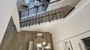 Un intérieur moderne avec un escalier, un canapé, une table basse et un lustre.