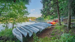 A row of canoes on a dock, surrounded by trees and a calm body of water.