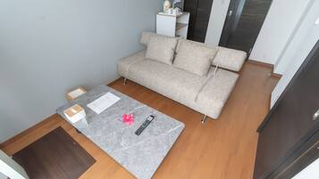 A room with a grey sofa, a small table with a remote control, and a white cabinet against the wall.