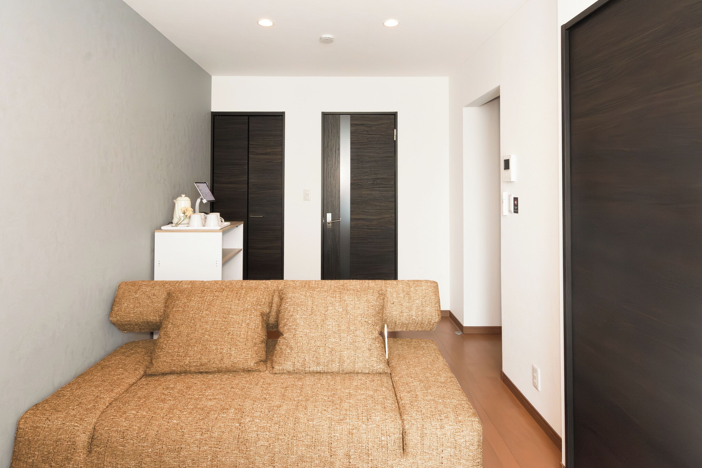 A modern room with a sofa, a small table with a lamp, and a wardrobe.