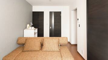 A modern room with a sofa, a small table with a lamp, and a wardrobe.