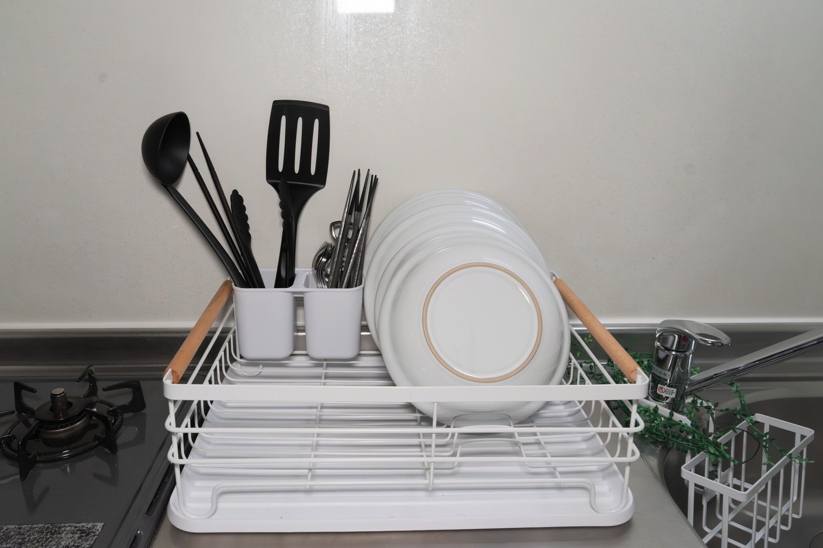 Una cocina con un escurreplatos que contiene platos, una espátula y utensilios.