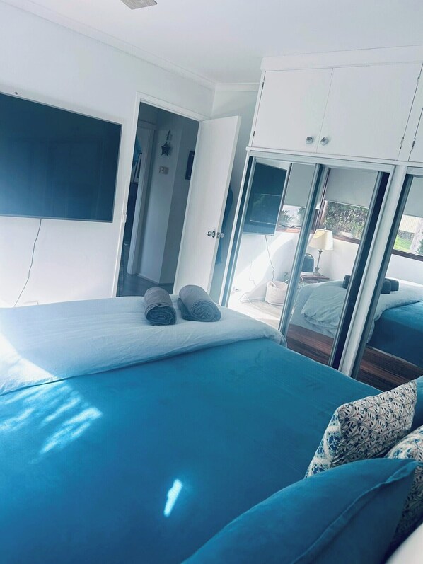 A bedroom with a bed, a wardrobe, and a view through a glass door.