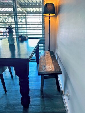 A dining area with a table and bench, a lamp, and a vase with a plant.