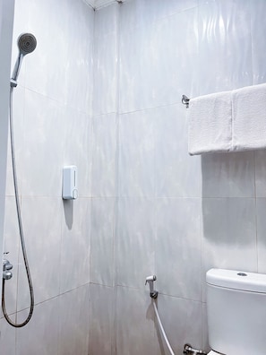 Un baño con azulejos blancos, ducha, toallero y retrete.