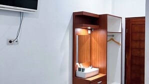 Une chambre à coucher comprenant un lit, une armoire, un miroir, un téléviseur fixé au mur et une prise de courant.