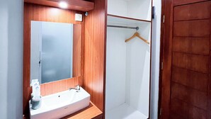 Une salle de bain avec un meuble-lavabo en bois, un miroir, un évier et une porte.