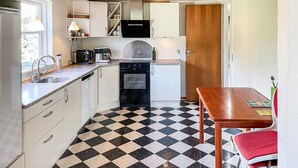 A compact kitchen with a checkered floor, a sink, a stove, and a dining table with a red chair. - Amazing home in søby ærø with WiFi (Søby Ærø)