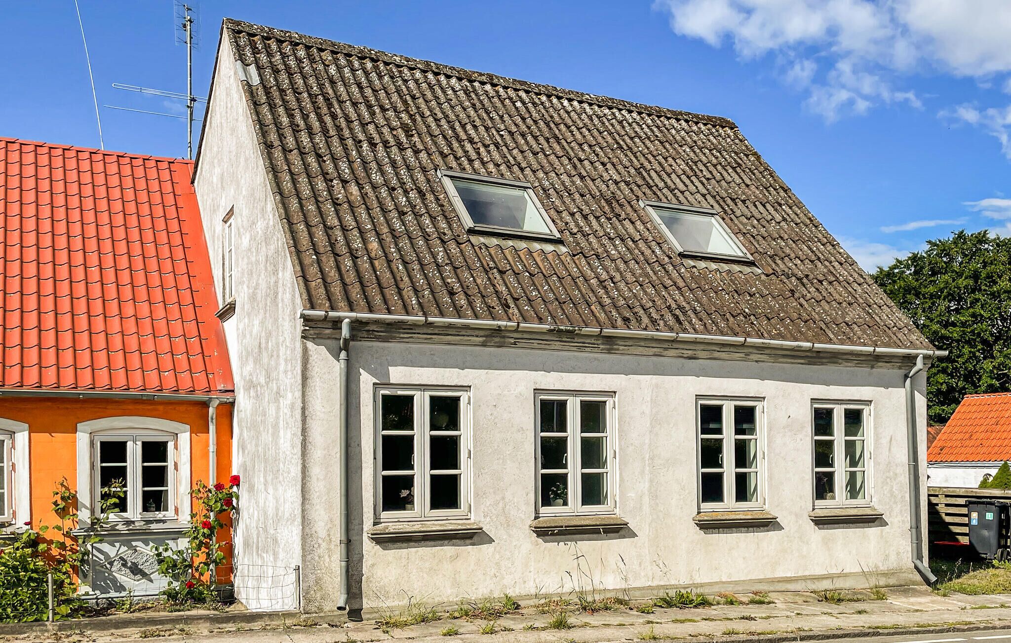 A two-story building with a sloped roof, multiple windows, and a visible antenna.