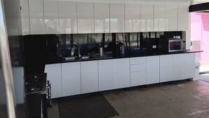 Una cocina moderna con armarios blancos, encimera negra y microondas.