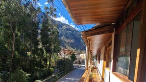 A wooden balcony with a view of a mountain and trees. - HOTEL PIEDRA BLANCA (Ollantaytambo)