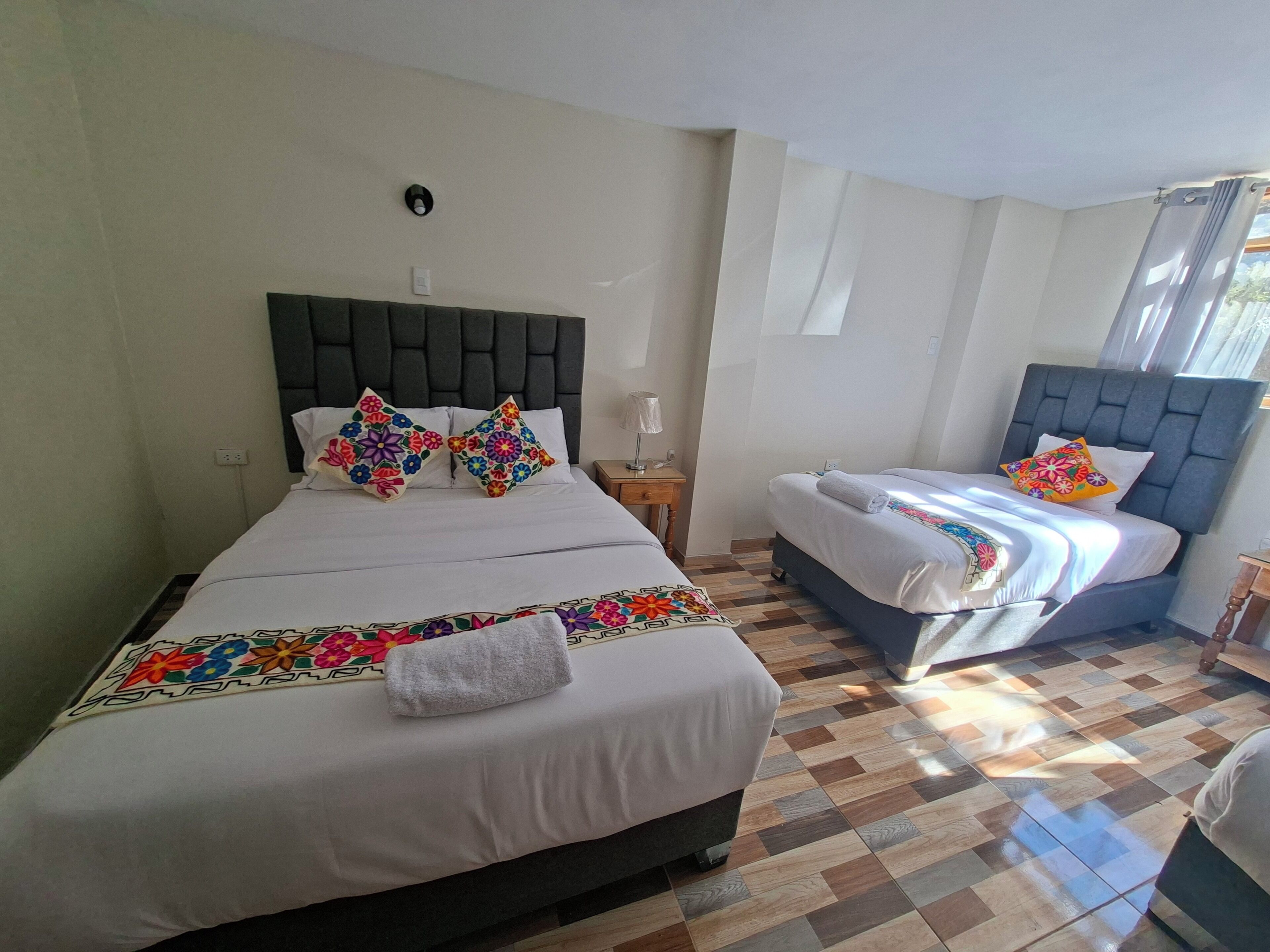 Una habitación de hotel con dos camas, piso a cuadros, cabecera y mesita de noche.