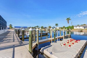 Ein Ufersteg mit Holzpfählen, einem Betonweg und einem Yachthafen mit Booten.