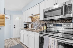A modern kitchen with white cabinets, a stainless steel microwave, and an oven. - Cozy coastal condo in St. James City with waterfront charm and easy island living. (Saint James City)