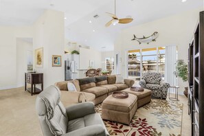 A spacious living room with a sectional sofa, a grey armchair, a patterned armchair, a coffee table, and a ceiling fan. - Island Escape in St. James City, Pool Home! (Saint James City)