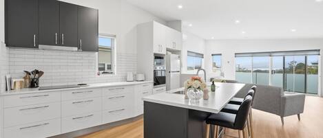 Una cocina moderna con armarios blancos, una isla central y un comedor con vistas.