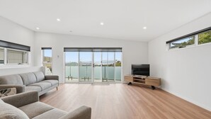 Una sala de estar moderna con un sofá, mueble para televisión y grandes puertas correderas de vidrio que dan a un balcón.