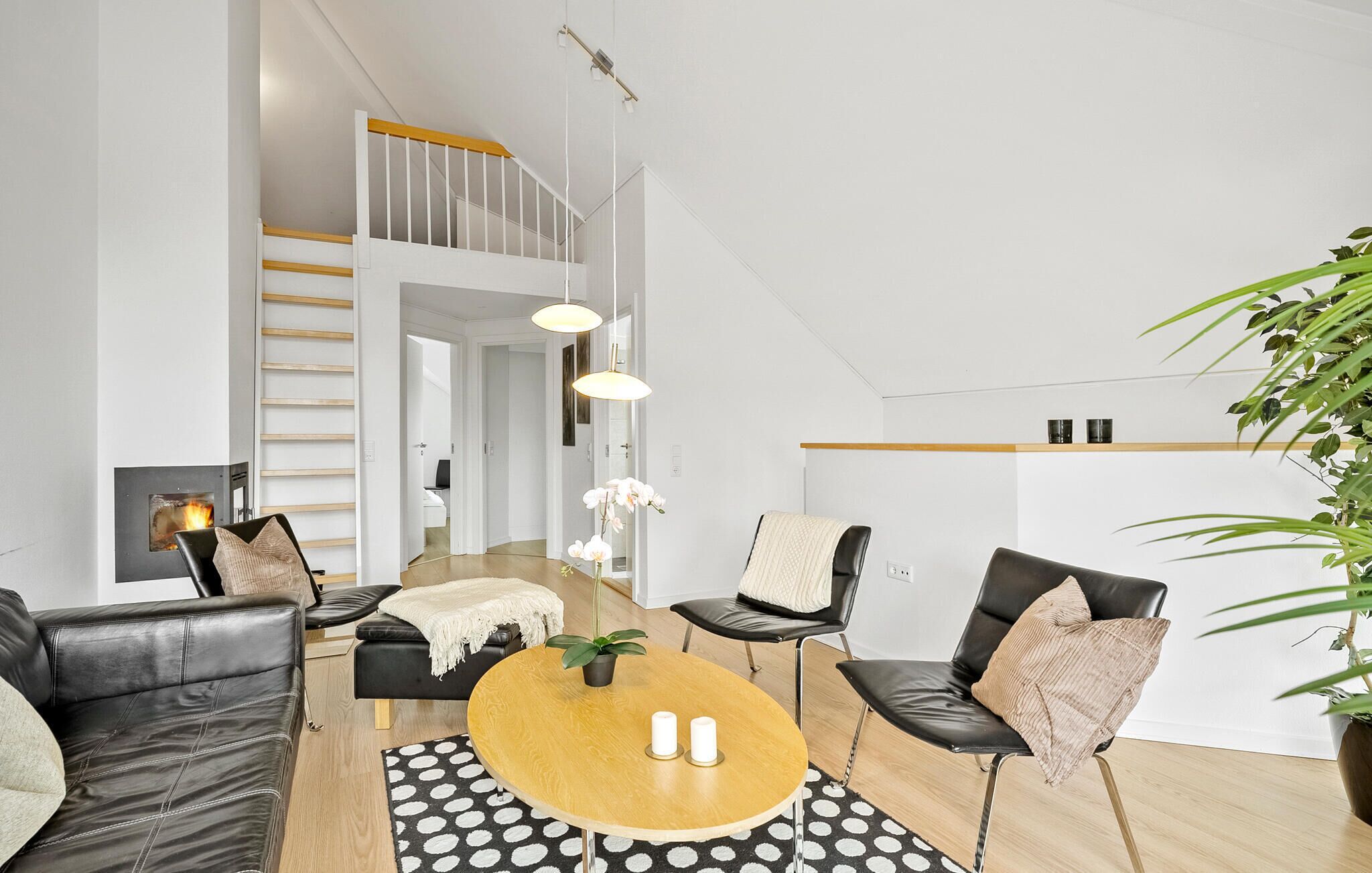 Una sala de estar moderna con chimenea, una escalera y un comedor.
