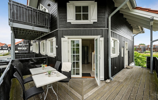 Ein schwarz-weißes Haus mit Balkon, einem Tisch mit Stühlen und einem Kühlschrank im Inneren.