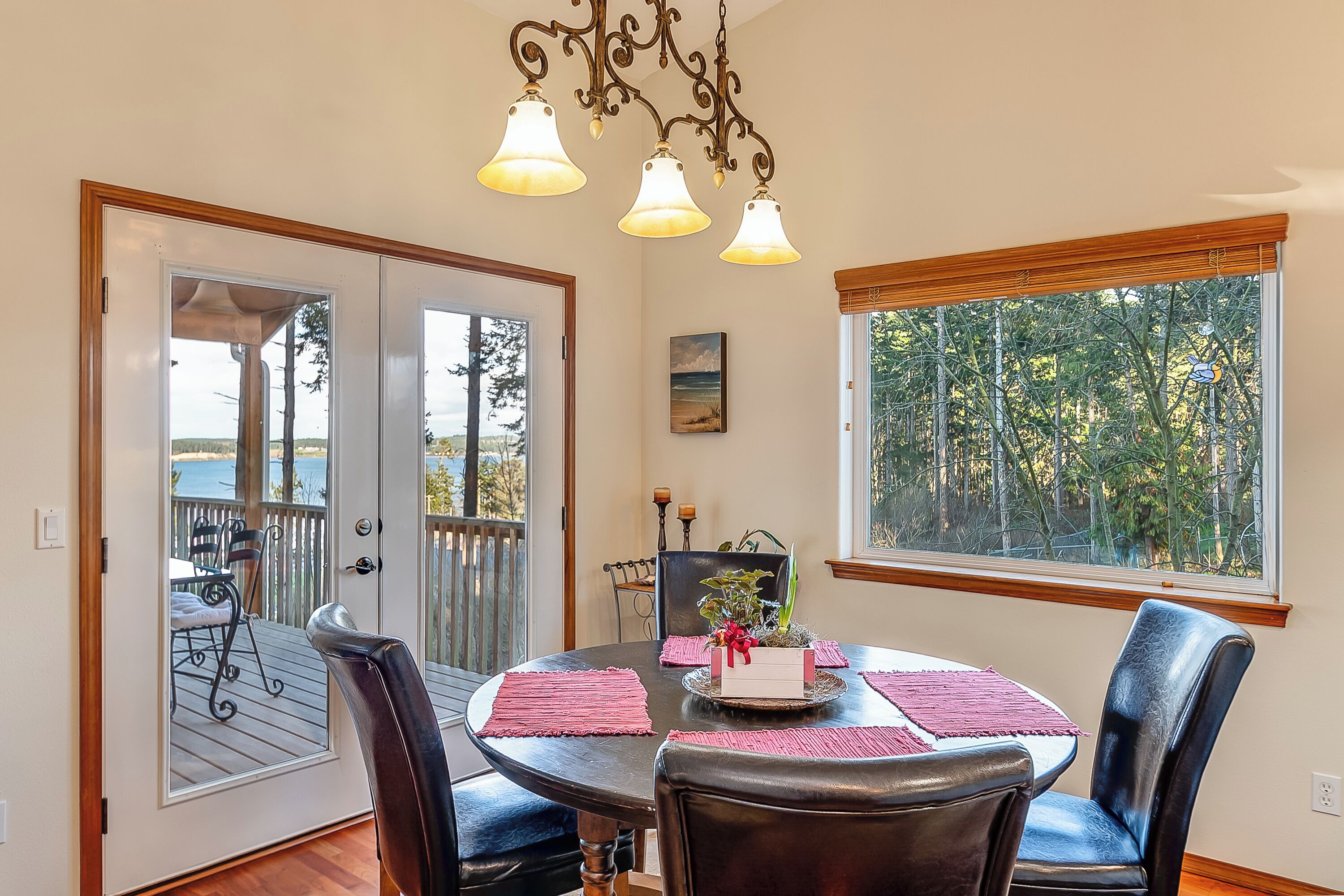 A dining area with a table, chairs, a chandelier, and a view through a window.