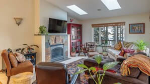 A living room with a fireplace, a television, a sofa, a coffee table, and a bookshelf.