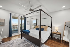 A four-poster bed with a ceiling fan, a nightstand with a lamp, and a view of a pool through a glass door. - PRIVATE HEATED POOL & SPA, PRIVATE BEACH, VOLLEYBALL & PICKLEBALL. BOAT DOCK (Pensacola)