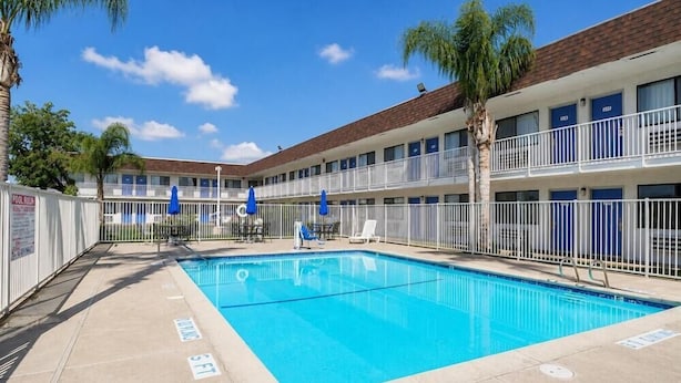 A hotel with a swimming pool, multiple balconies, and palm trees. - Motel6 Lost Hills, CA (Lost Hills)