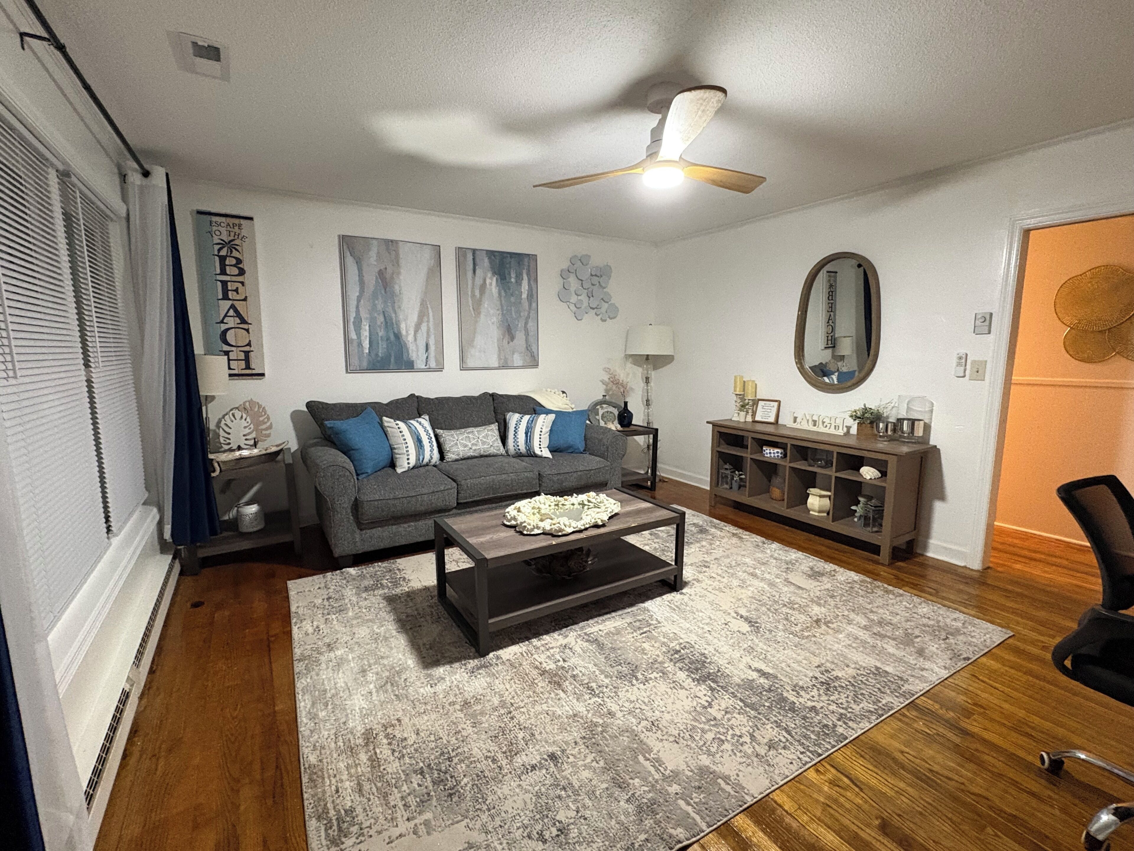 Ein Wohnzimmer mit grauem Sofa, Couchtisch, Beistelltisch und Bücherregal.