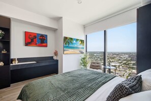 A modern bedroom with a large bed, a view of a cityscape through a floor-to-ceiling window, and artwork on the walls. - Deluxe E11EVEN Suite with Elite Amenities (Miami)
