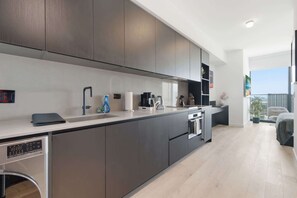 A modern kitchen with a built-in oven, a coffee station, and a view of the city. - Deluxe E11EVEN Suite with Elite Amenities (Miami)