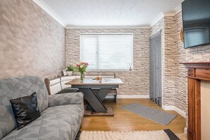 Ein gemütlicher Wohnbereich mit Esstisch, einer Couch, Kamin und einer Steinwand.
