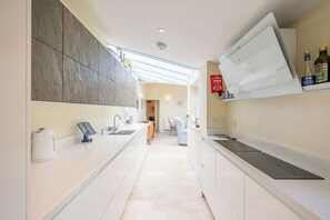 A modern kitchen with a central island, a built-in oven, and a microwave. - The Light House, Southwold (Southwold)