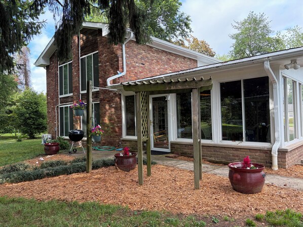 A brick house with a covered patio, large windows, and hanging flower pots.